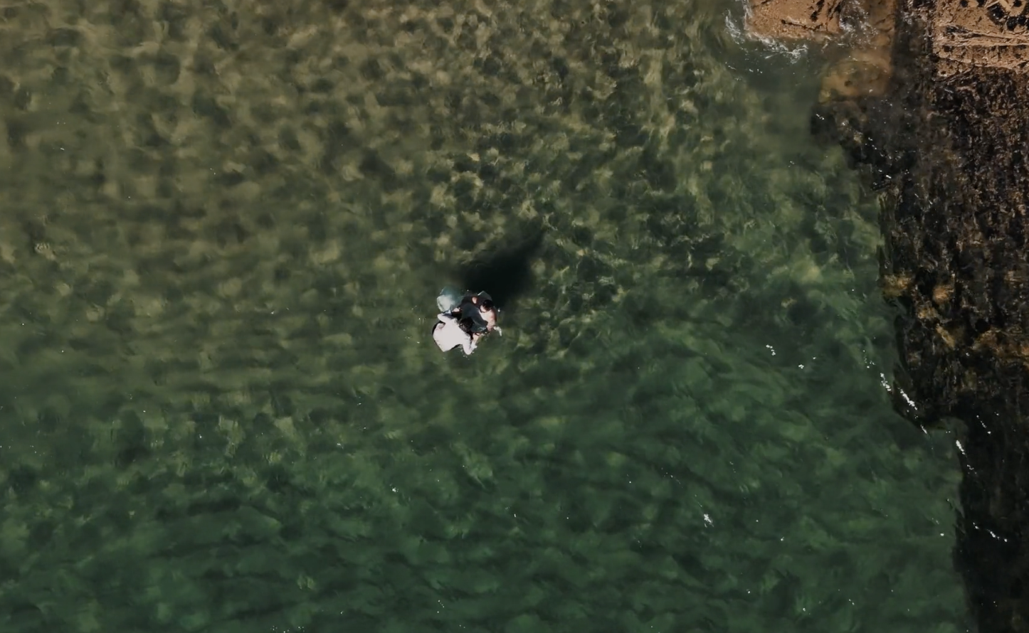 bride and bride in the sea after their wedding on a Cornish beach